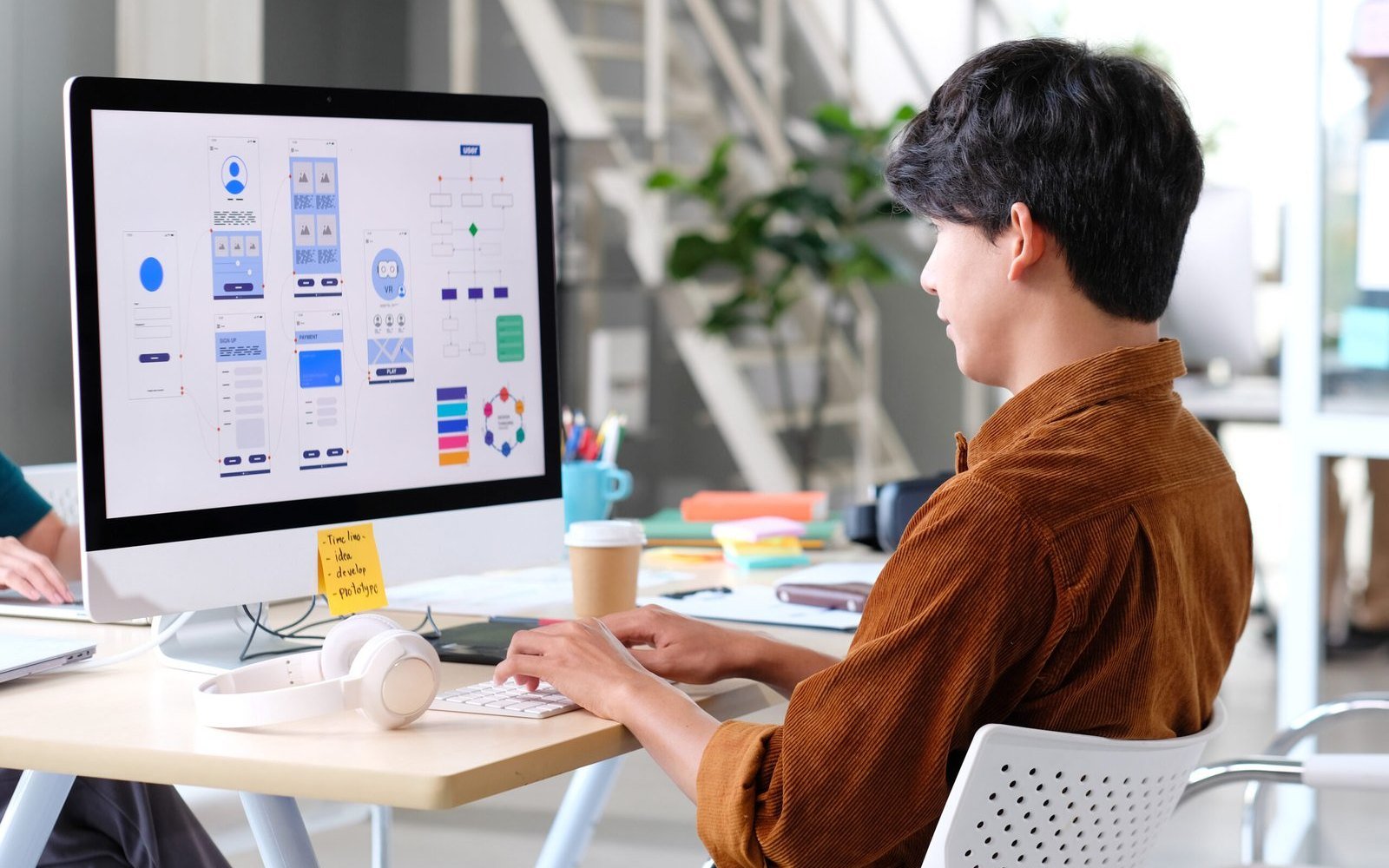 A designer laying out website screens on a large monitor.